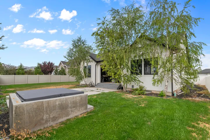 Expansive rear yard with manicured lawn, established landscaping, and privacy fencing