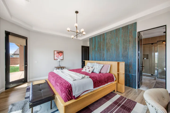 Spacious room featuring a textured accent wall, wood-finish flooring, and a contemporary chandelier