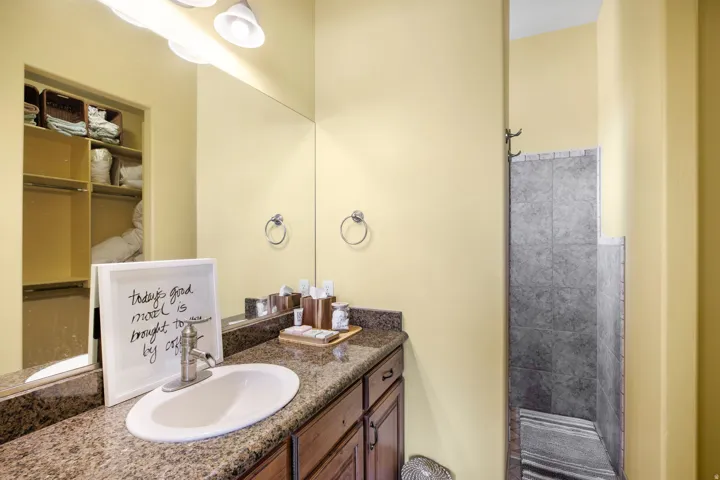 Bathroom featuring a single vanity with an oval basin, a speckled countertop, and wood-finish cabinetry