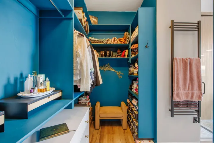 Custom walk-in closet featuring vibrant blue shelving, built-in storage, and wood-finish flooring