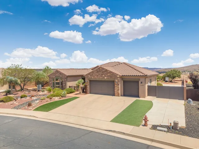 Mediterranean-style architecture featuring a tile roof, brick and stucco exterior, and dual garage doors