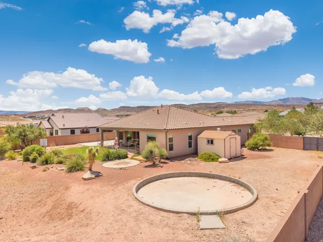 Southwestern-style residence featuring a covered patio, a detached storage shed, and a circular raised garden bed