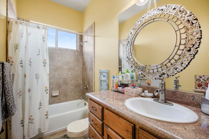Bathroom featuring a vanity with a granite-style countertop, an undermount sink, and wood-finish cabinetry