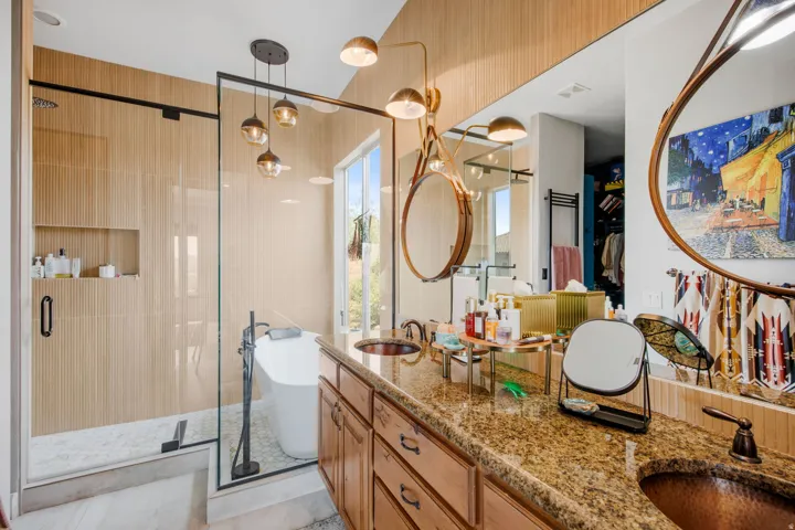 Spacious bathroom featuring a freestanding tub, glass-enclosed shower, and a dual-sink vanity with copper-finish basins