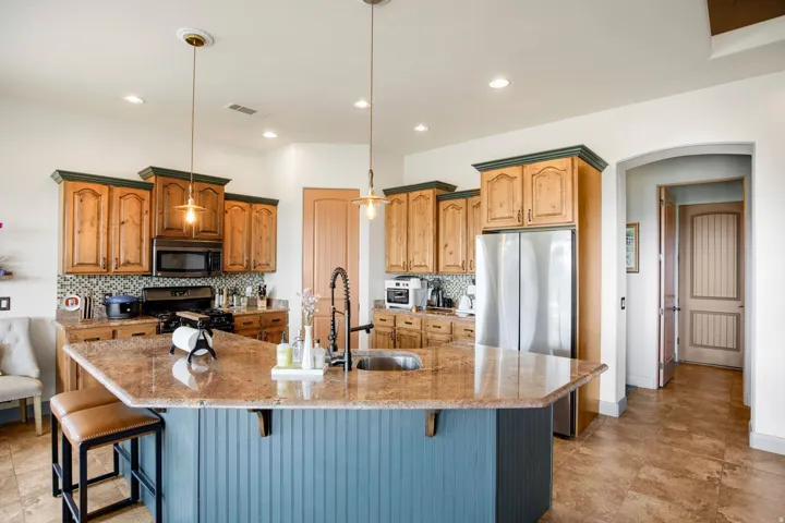 Spacious kitchen featuring a large island with a composite stone countertop, beadboard paneling, and an undermount sink with a gooseneck faucet