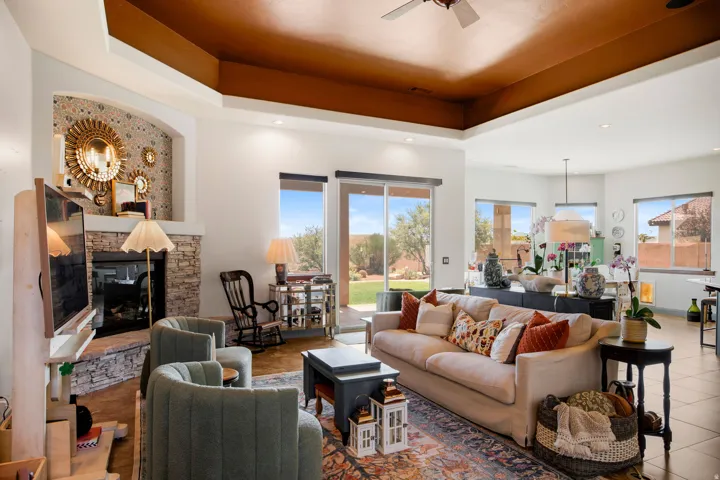 Spacious living area featuring a stacked stone fireplace, tray ceiling, and recessed lighting