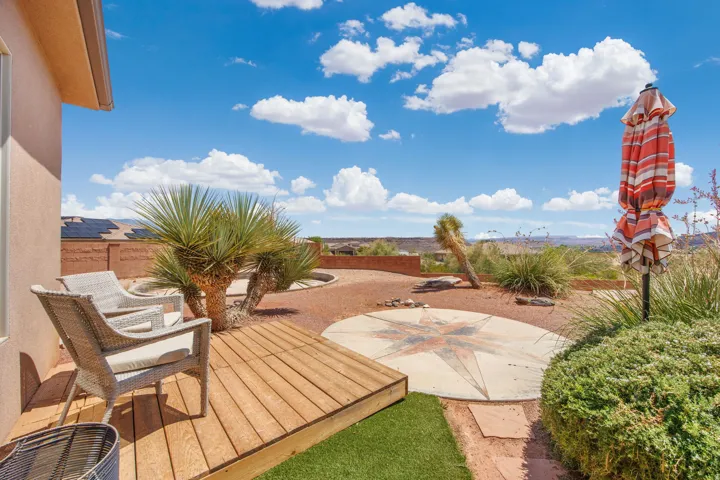 Expansive rear yard featuring a wood-finish deck, artificial turf, and a concrete patio with an inlaid compass design
