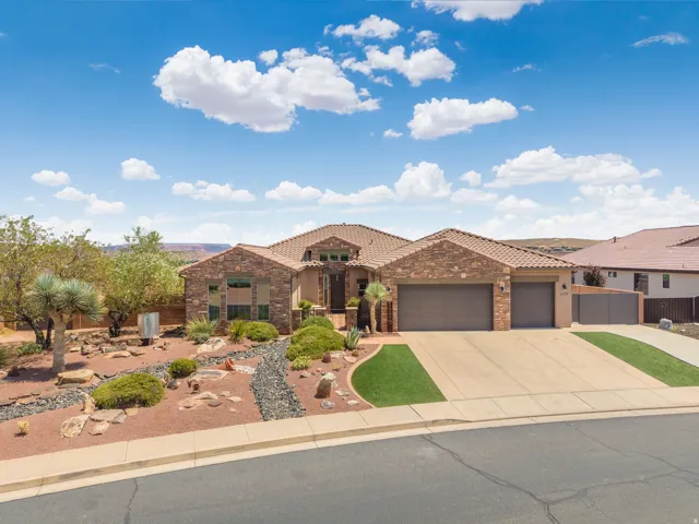 Stucco and stone facade home featuring a tile roof, two-car garage, concrete driveway, and desert-style landscaping