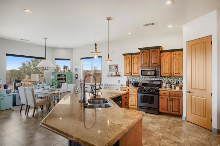 Open-concept kitchen and dining area featuring a large island with sink, tile flooring, two-tone wood cabinetry, a mosaic tile backsplash, and recessed lighting