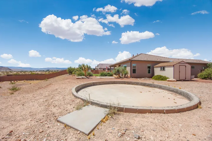 Property exterior featuring an empty pool basin, a detached storage shed, and a tiled roofline