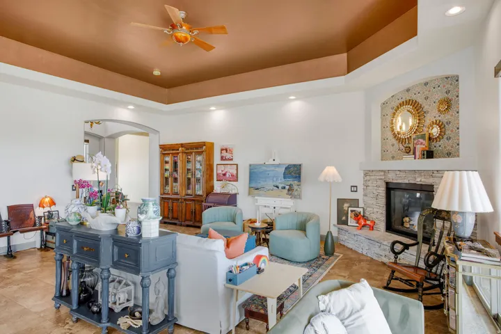 Living area featuring a tray ceiling with a ceiling fan, recessed lighting, and tile flooring