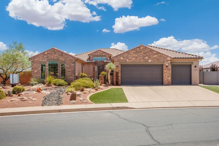 Stone facade residence featuring a tile roof, a three-car garage, and a concrete driveway