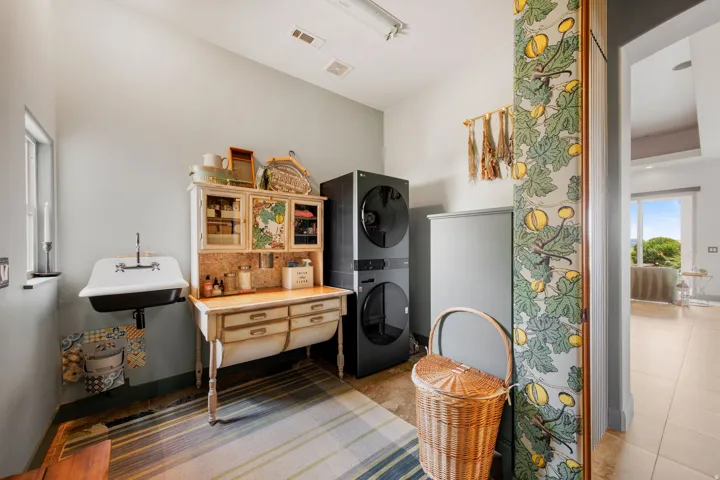 Functional laundry area featuring a wall-mounted utility sink, built-in cabinetry, and tile flooring