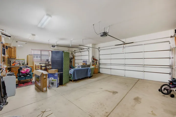 Spacious garage featuring two overhead doors, concrete flooring, and multiple ceiling-mounted light fixtures