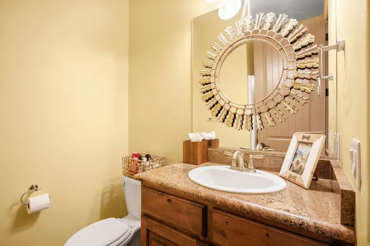 Bathroom vanity featuring a granite countertop, undermount sink, and wood-finish cabinetry