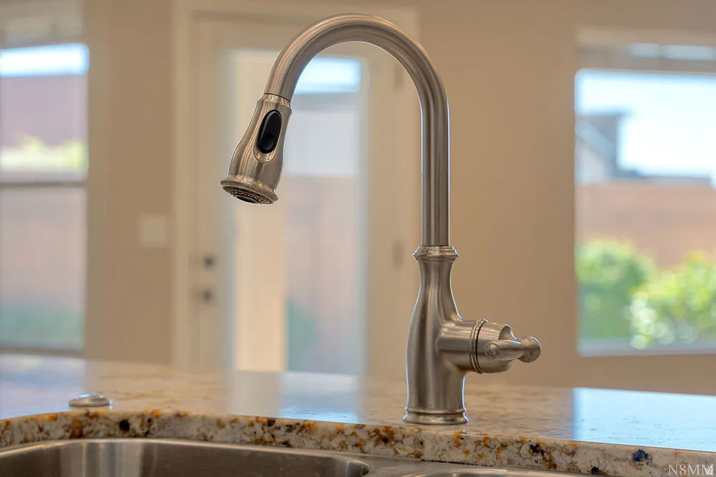 Brushed nickel gooseneck faucet with an integrated pull-down sprayer set into a multi-toned stone countertop with an under-mount sink