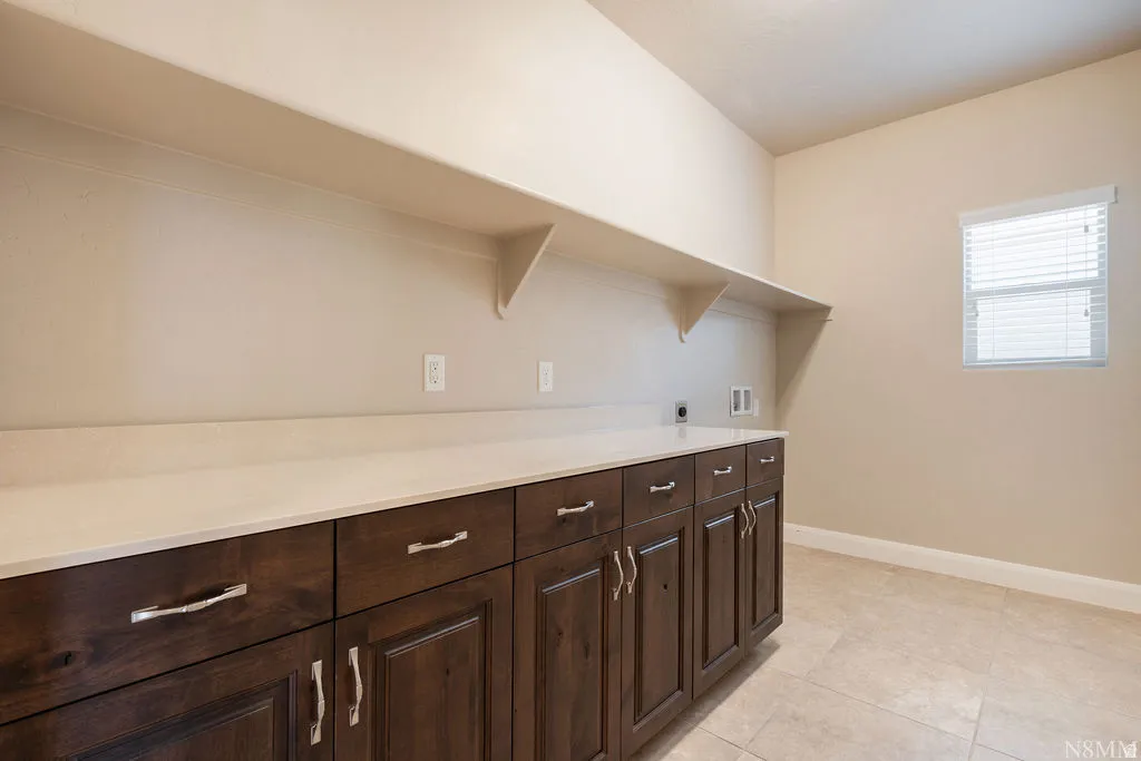 Extensive dark wood-finish cabinetry, light-toned countertop, integrated shelving, and tiled flooring