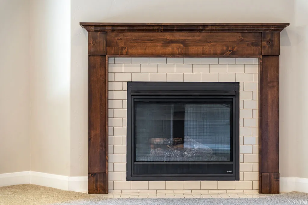 Wood-stained fireplace surround with a mantel, subway tile hearth, and dark-finished firebox