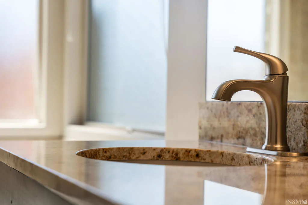 Polished bronze tone faucet with an undermount sink, set into a stone countertop