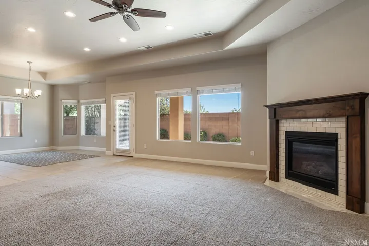 Spacious interior featuring a fireplace with a wood mantle and tile surround, multiple windows, a ceiling fan, and recessed lighting