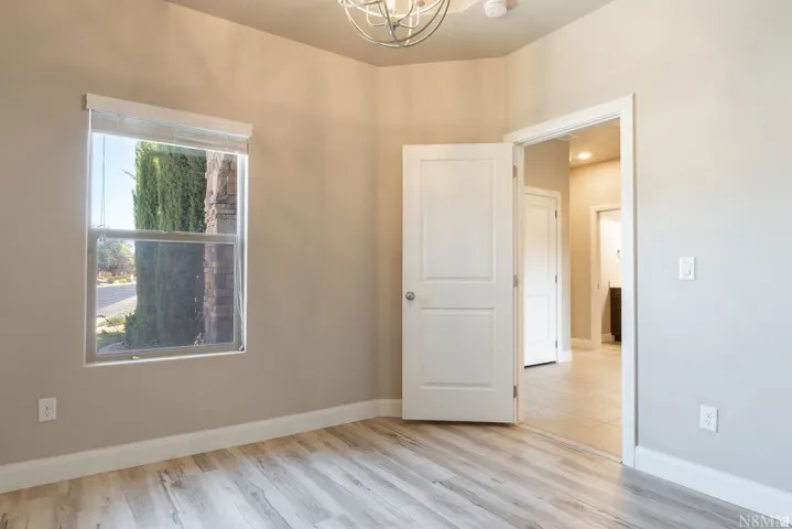 Wood-finish flooring, neutral wall tones, and a double-pane window with a light-filtering shade
