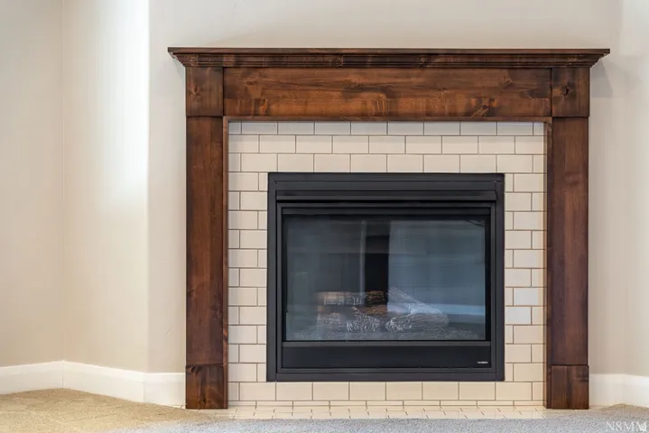 Wood-stained fireplace surround with a mantel, subway tile hearth, and dark-finished firebox