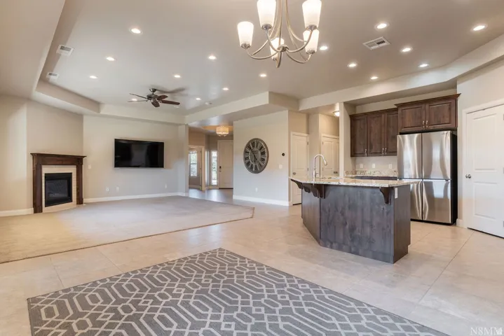 Open-concept living space featuring a fireplace with wood-finish mantel, recessed lighting, and a ceiling fan
