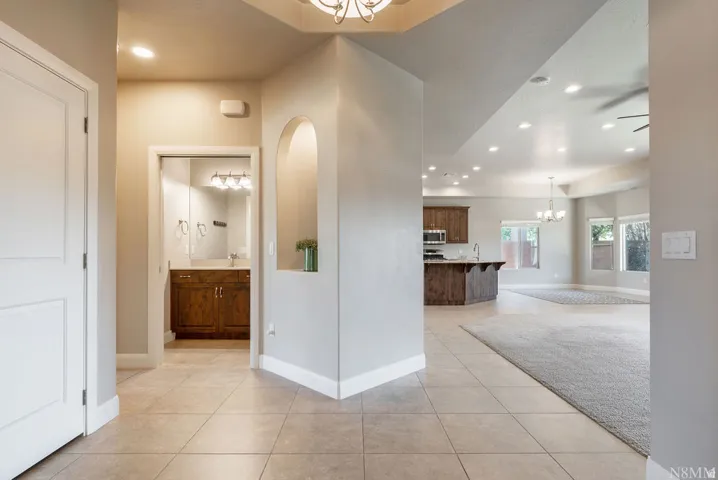 Tile flooring, recessed lighting, arched wall niche, wood cabinetry, and a vanity with a rectangular sink