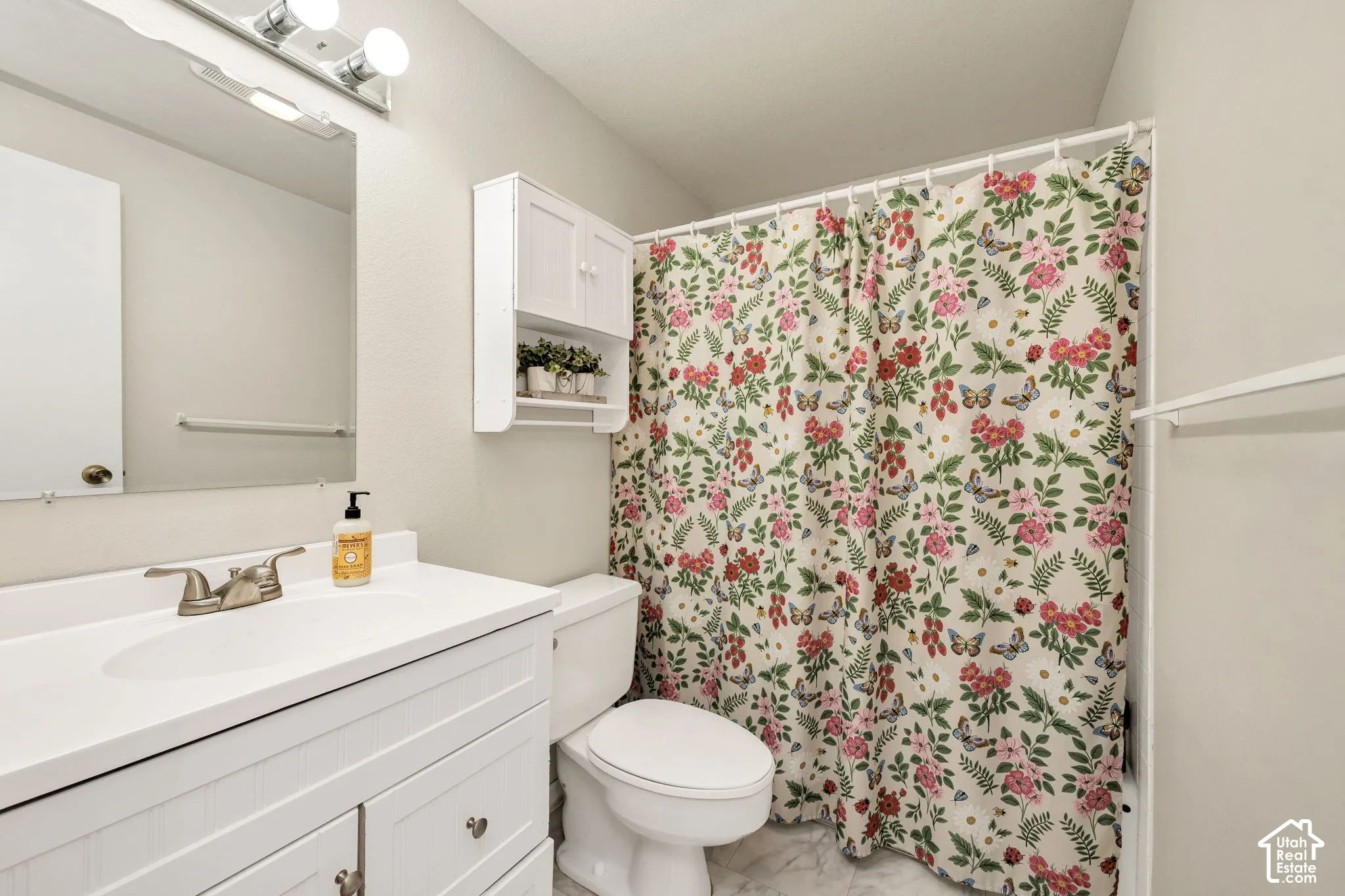 White vanity with brushed nickel fixtures, wall-mounted mirror, and overhead light bar