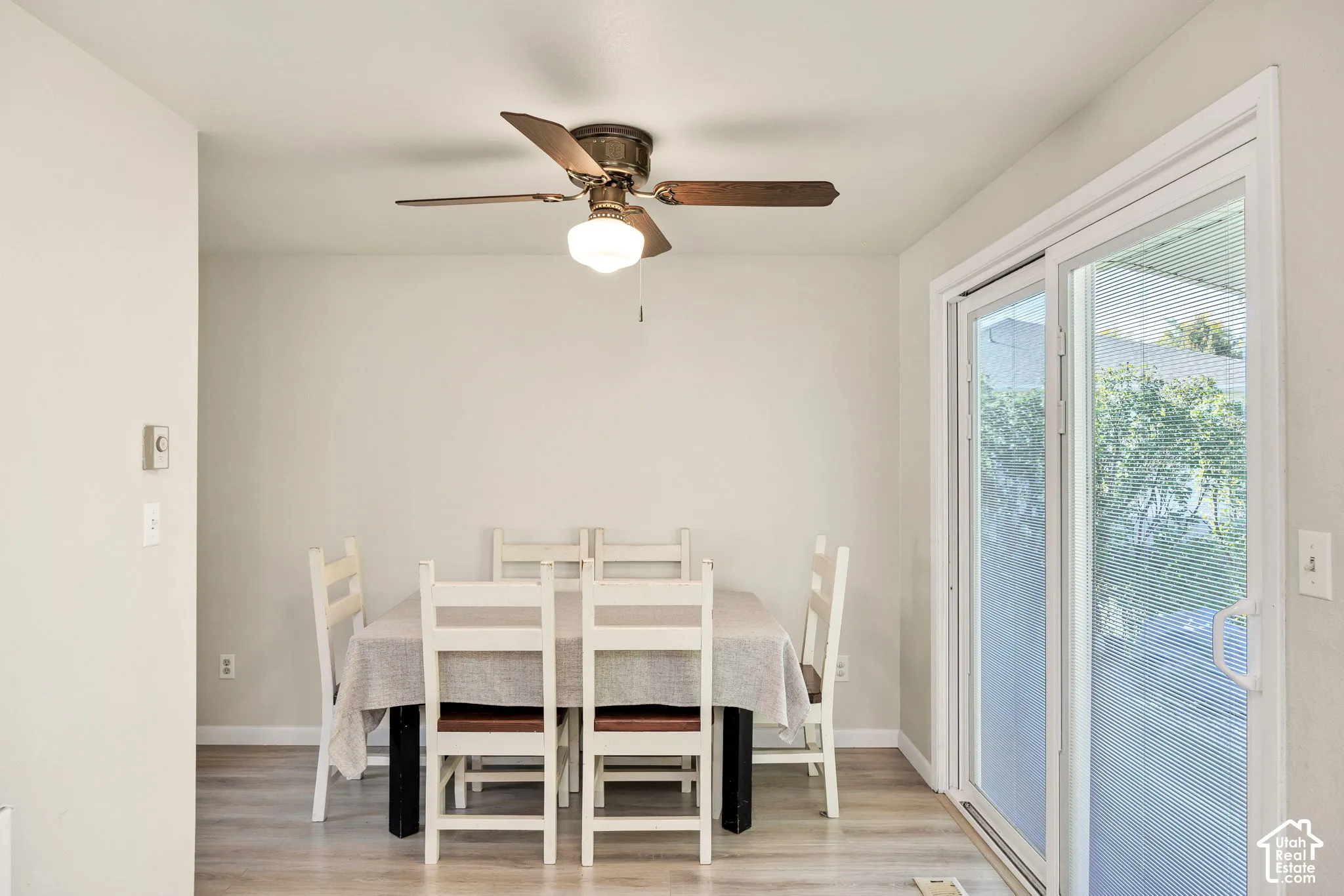 Wood-finish flooring, ceiling fan with integrated lighting, and a sliding glass door
