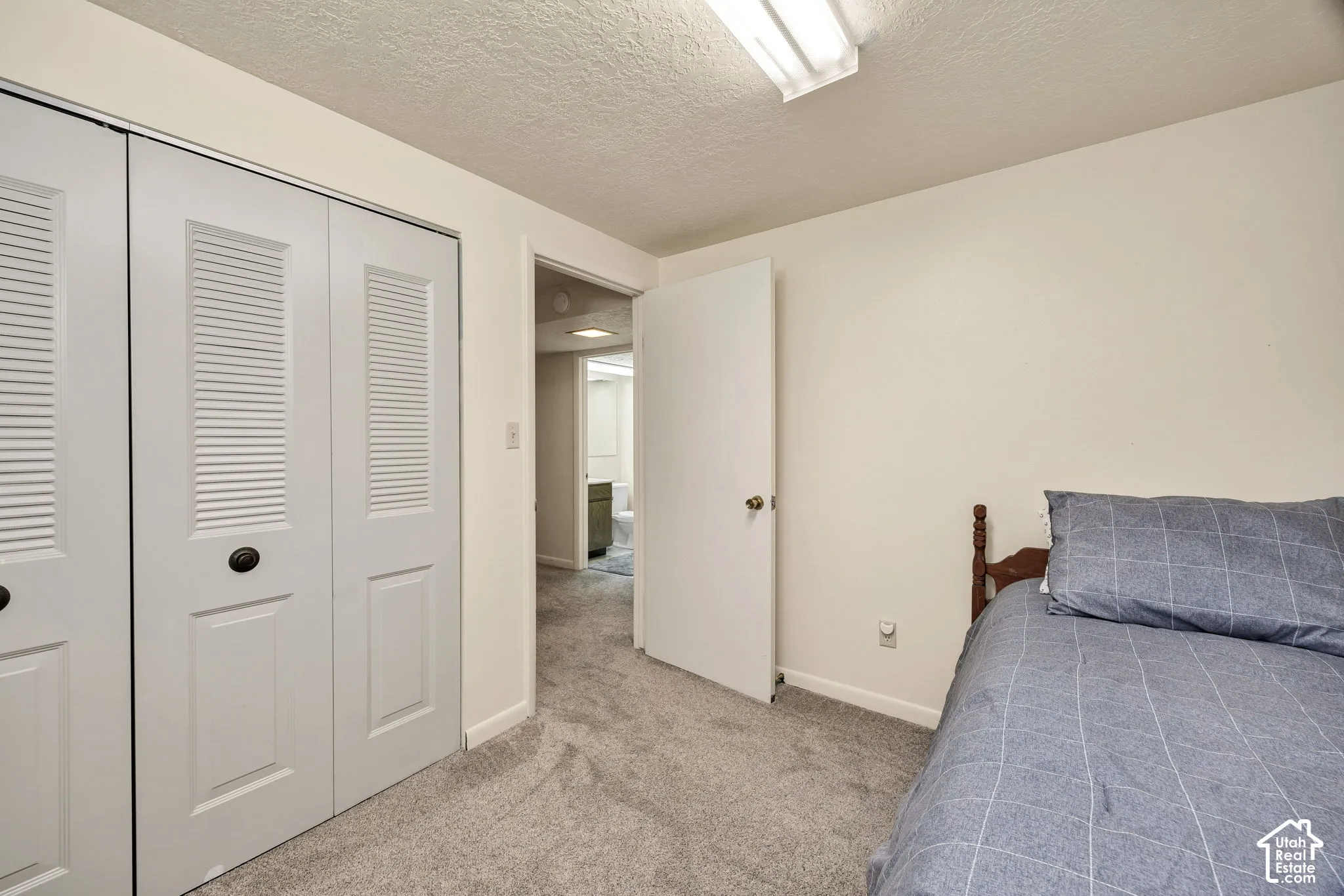Louvered bi-fold closet doors and neutral carpeting