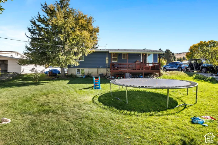 Expansive green lawn with mature trees and a multi-level deck