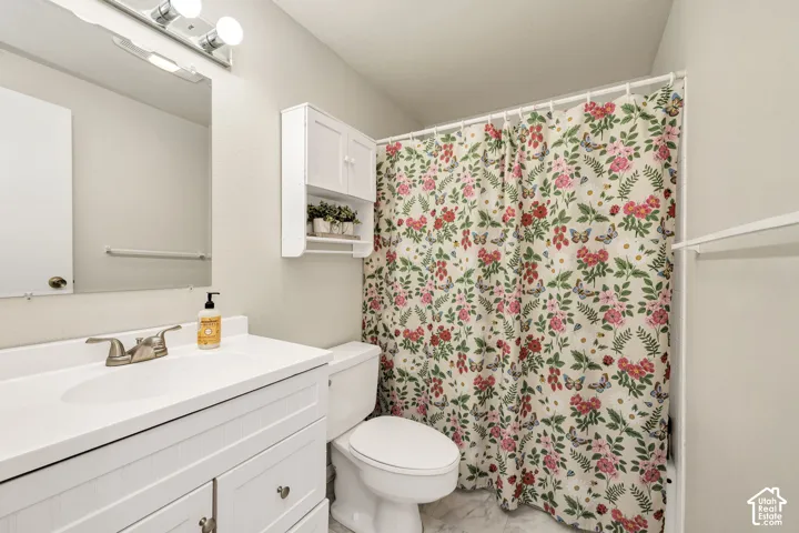 White vanity with brushed nickel fixtures, wall-mounted mirror, and overhead light bar