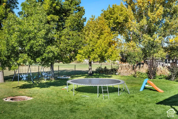 Expansive grassy yard with mature trees and a metal fence