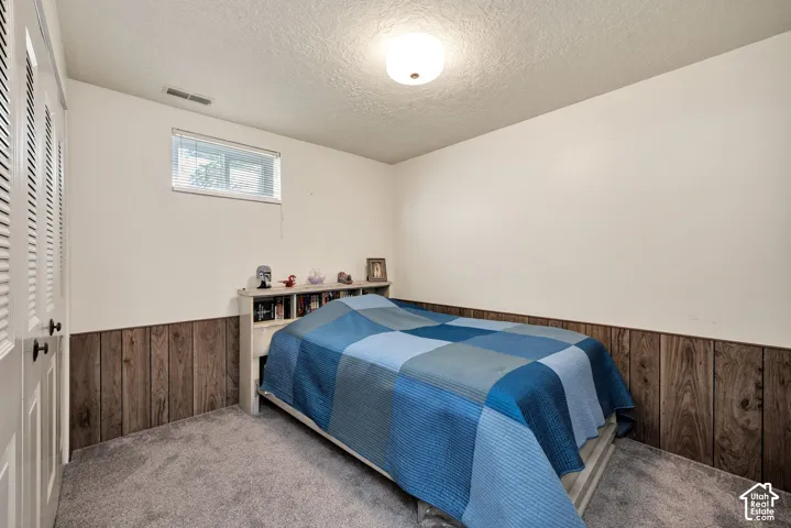 Carpeted flooring, wood-panel wainscoting, and a single window with blinds