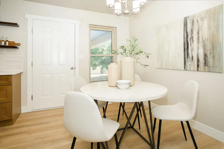 Light wood-finish flooring, white paneled door, kitchen cabinetry with white countertops, and a window with exterior scenery