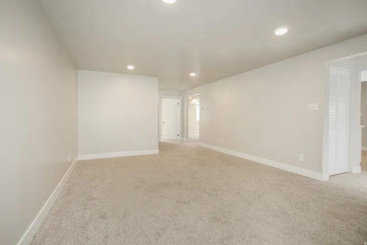 Plush carpet flooring, recessed ceiling lighting, light neutral wall paint, white trim, and interior doors