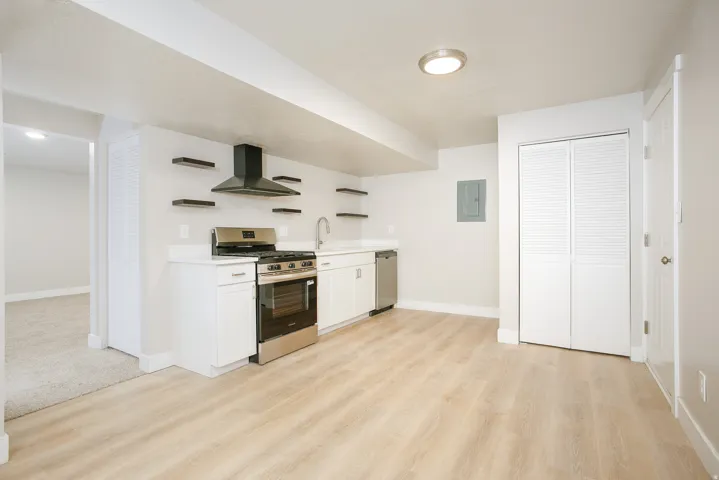 Full kitchen featuring stainless steel appliances, white cabinetry, open shelving, and wood-finish flooring