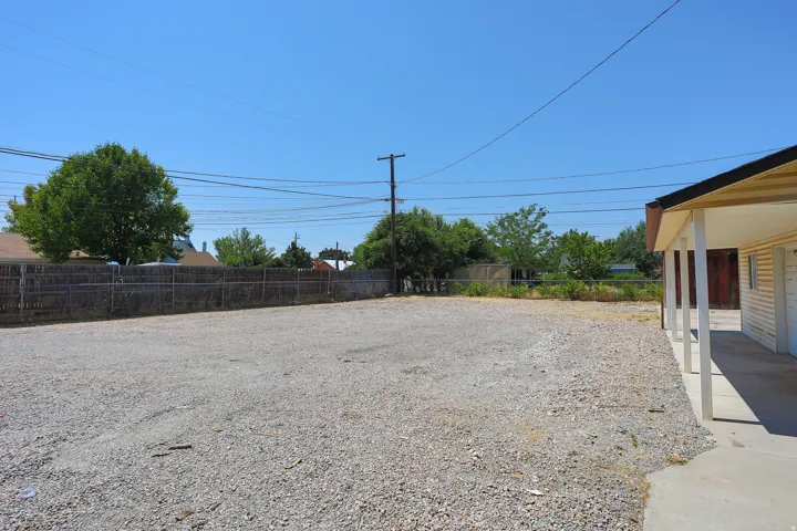 Gravel lot with perimeter fencing and a covered patio area
