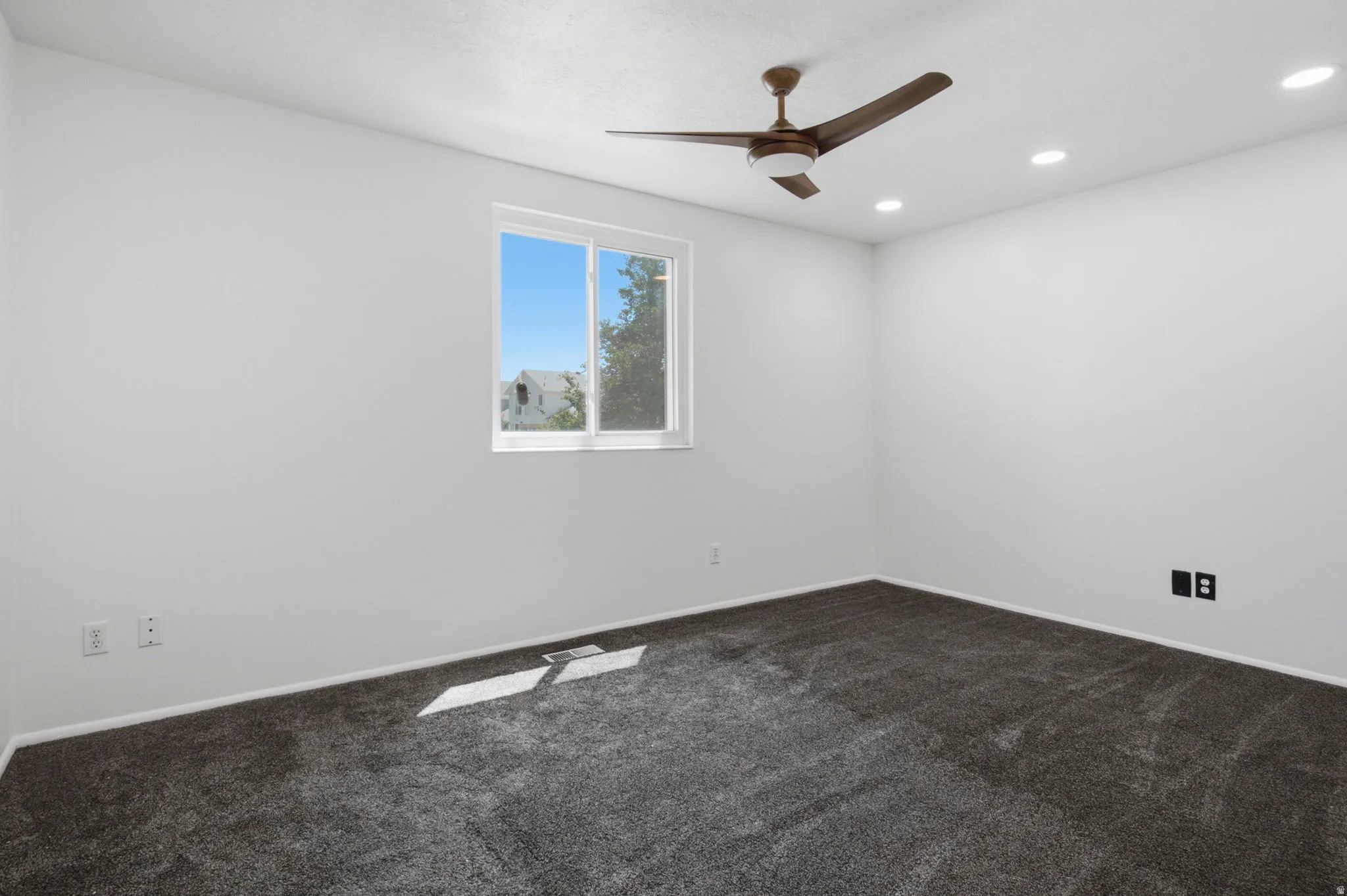 Recessed lighting, a ceiling fan with integrated light, a window, and gray carpeting