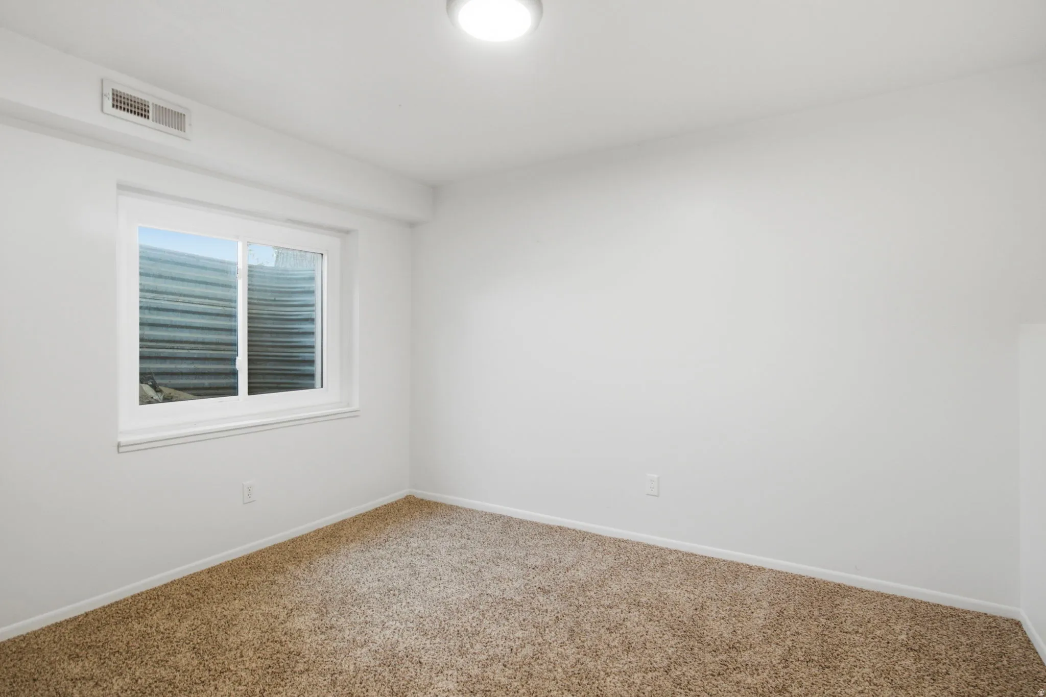Neutral wall finishes, carpeted flooring, and a single window