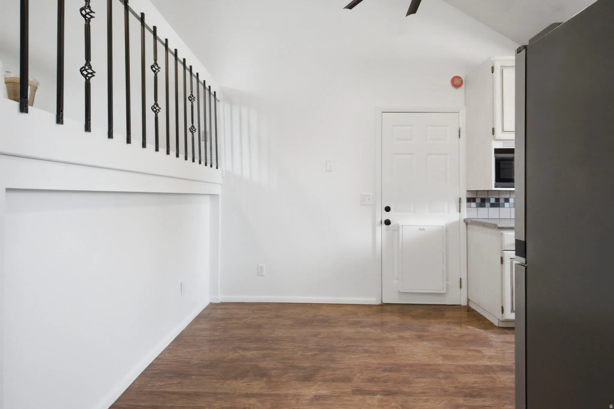 Wood-finish flooring, white walls, and a black wrought iron railing