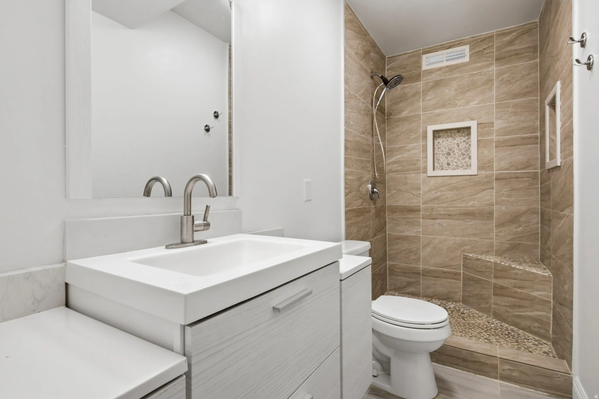 Vanity with integrated sink, brushed nickel faucet, and white countertop