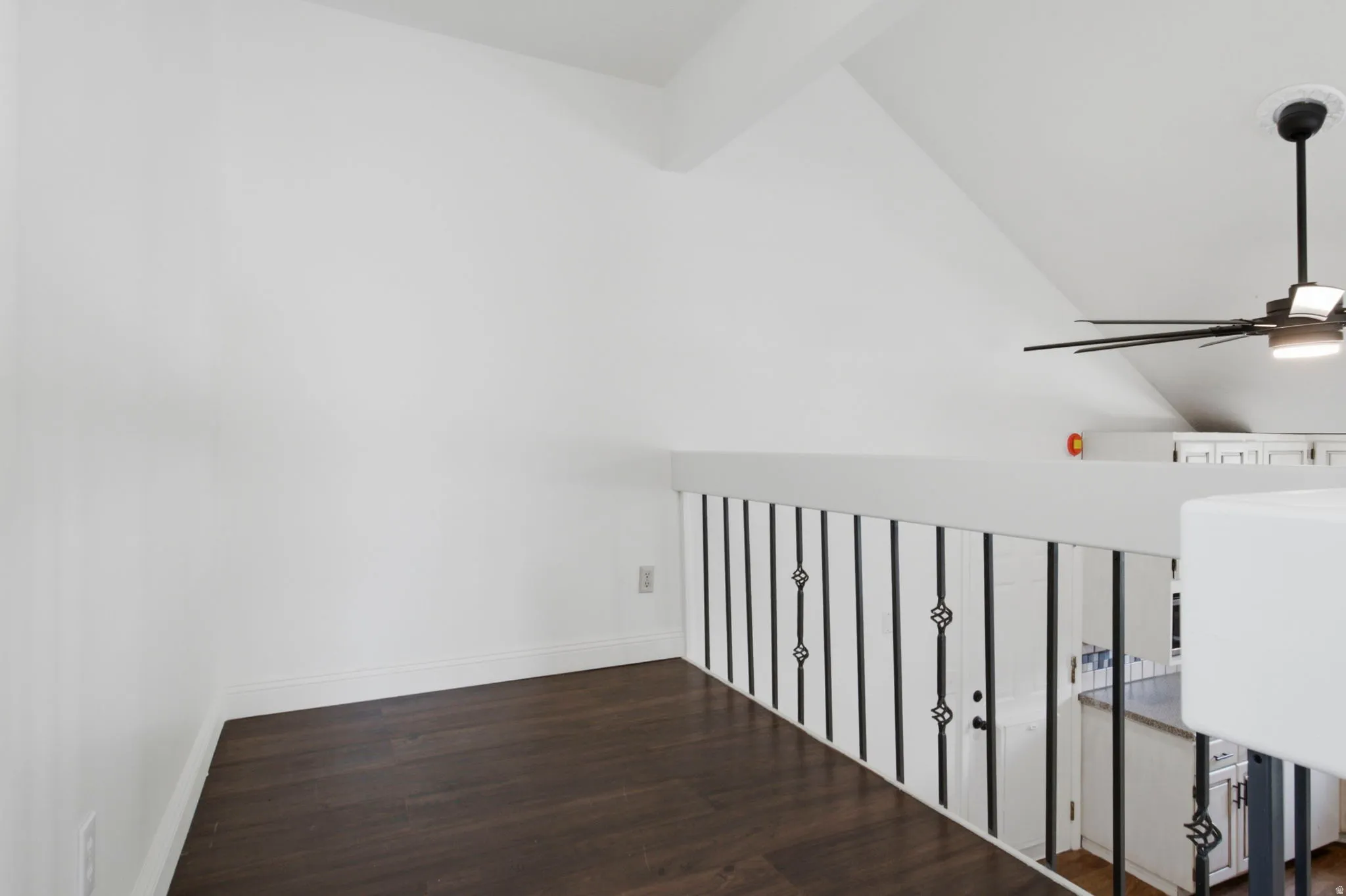 Loft space with angled ceilings, wood-finish flooring, and white walls