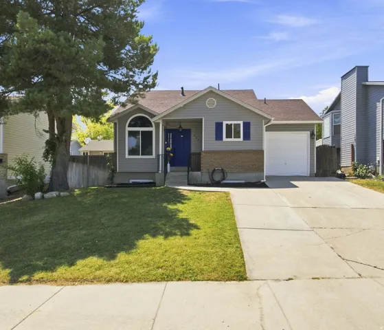 Gray siding exterior with a partial brick facade, a vibrant blue front door, an arched window, and an attached single-car garage