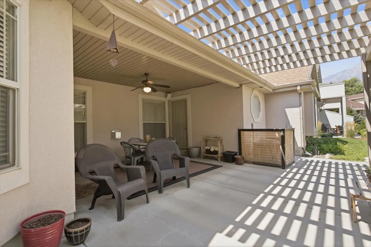 Covered patio with a built-in ceiling fan, adjacent to an open pergola structure