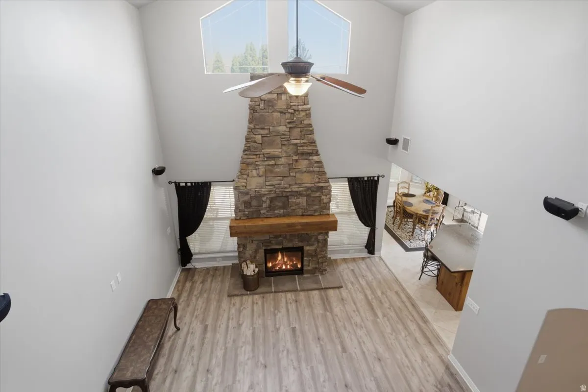 Vaulted ceilings with an angular window, stone fireplace with a wood-finish mantel, wood-finish flooring throughout, and an open-concept layout
