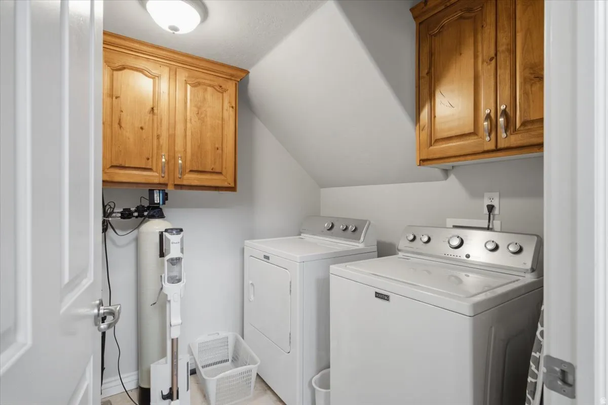 Dedicated laundry area featuring wood-finish cabinetry, light grey wall paint, and overhead lighting