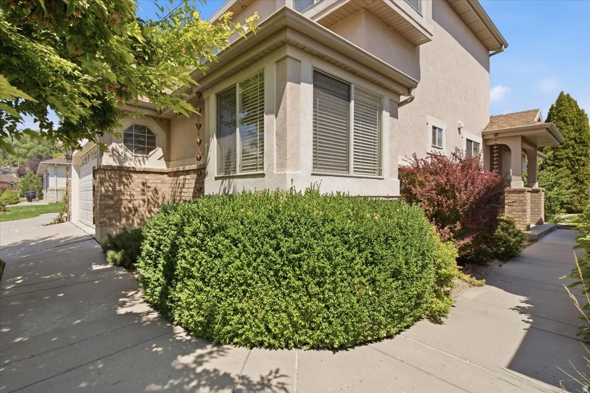 Stucco exterior with brick detailing and mature landscaping