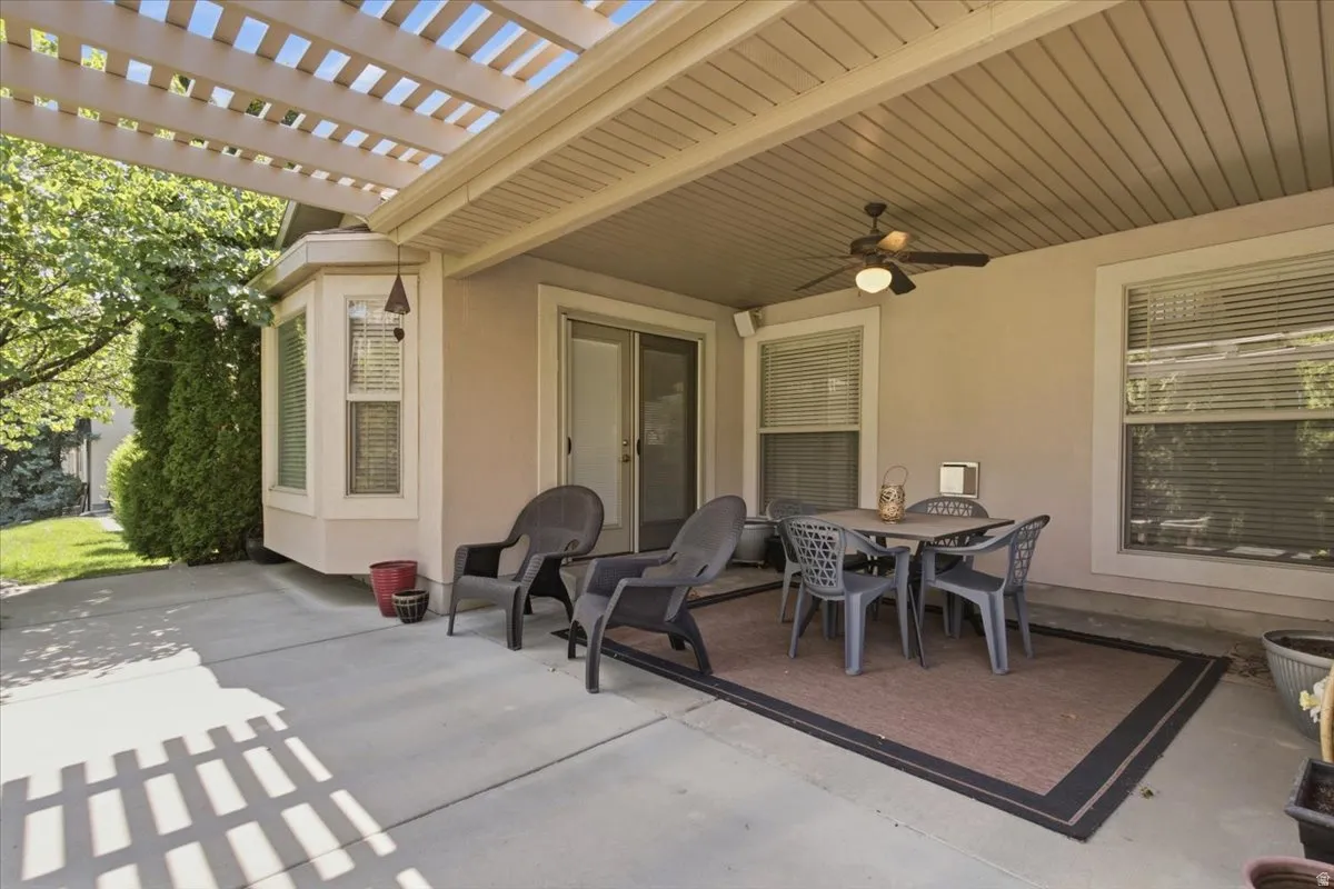 Covered patio with a ceiling fan, a bay window, and a sliding glass door